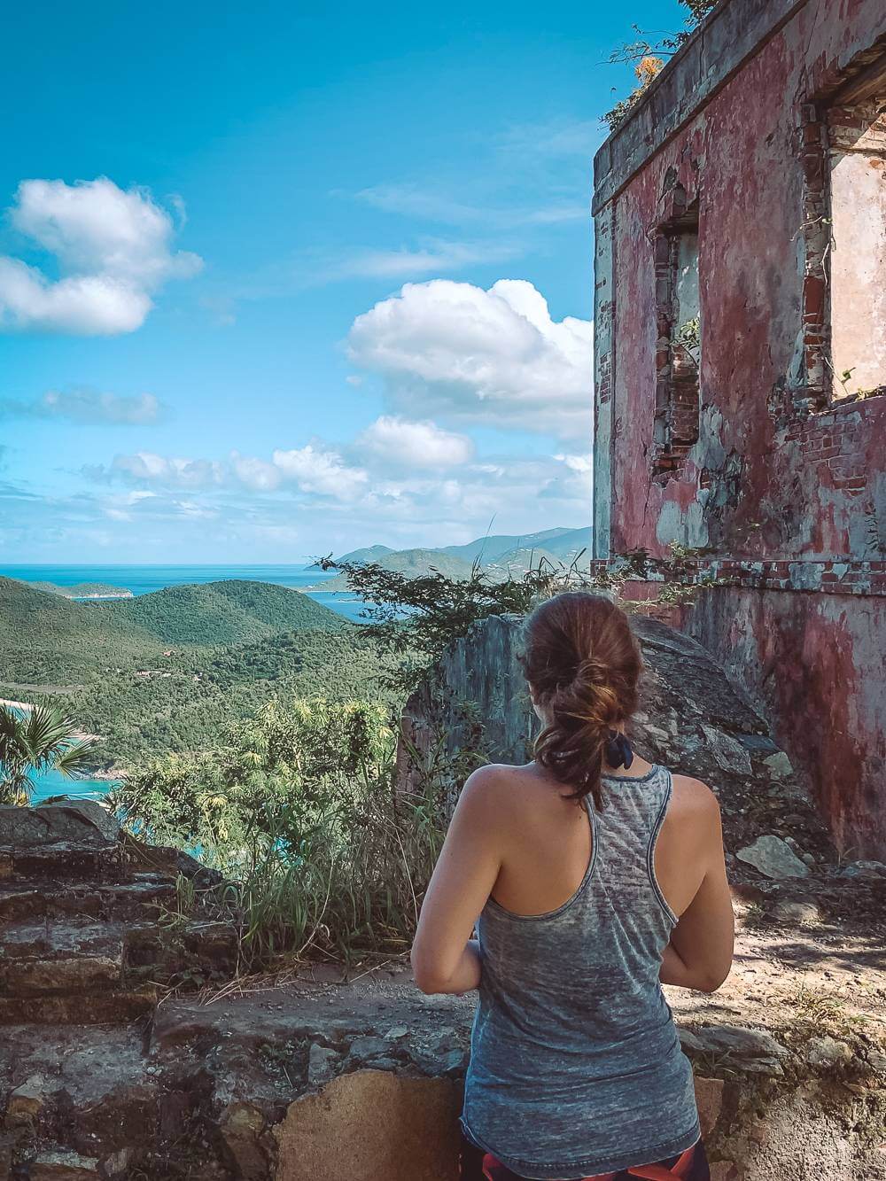  брюнетка в майке рядом с руинами плантации с видом на залив Махо 