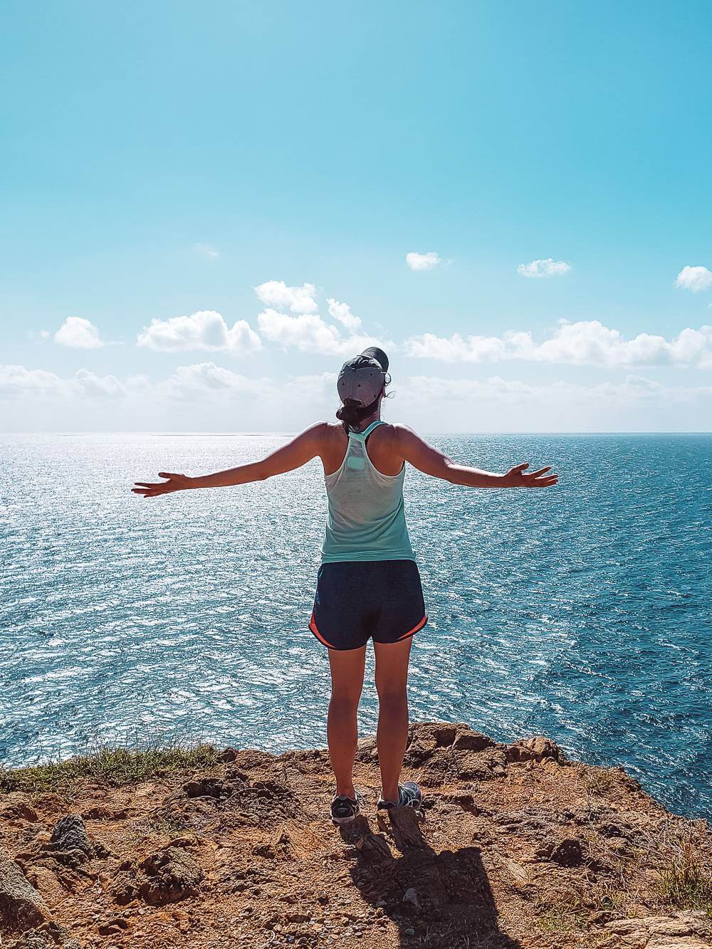  девушка, стоящая в конце тропы Баран-Хед с видом на голубые карибские воды острова Сент-Джон, США 